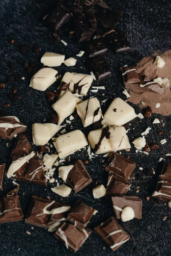 a couple of pieces of chocolate sitting on top of a table, inspired by Joris van der Haagen, trending on pexels, shattered, dark and white, ingredients on the table, thumbnail
