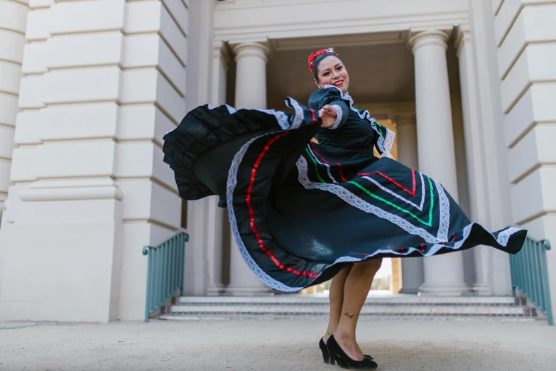 a woman in a dress is dancing in front of a building, folklorico, striking a pose, bay area, square