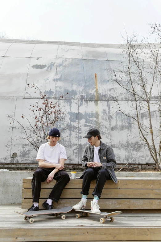 a couple of men sitting on top of a wooden bench, unsplash, graffiti, boards of canada, next to a plant, catalog photo, multiple stories