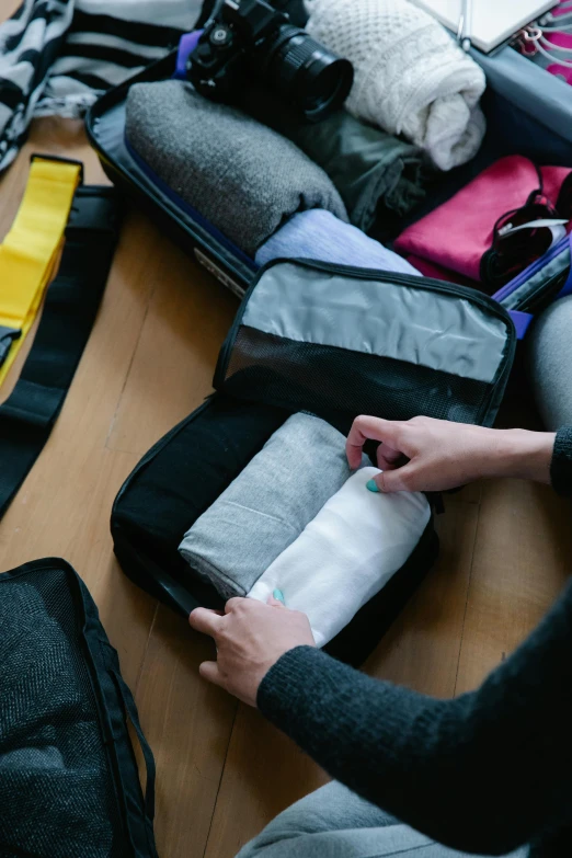 a woman packing her luggage on the floor, by Nina Hamnett, trending on unsplash, several layers of fabric, fully space suited, patagonian, high angle close up shot