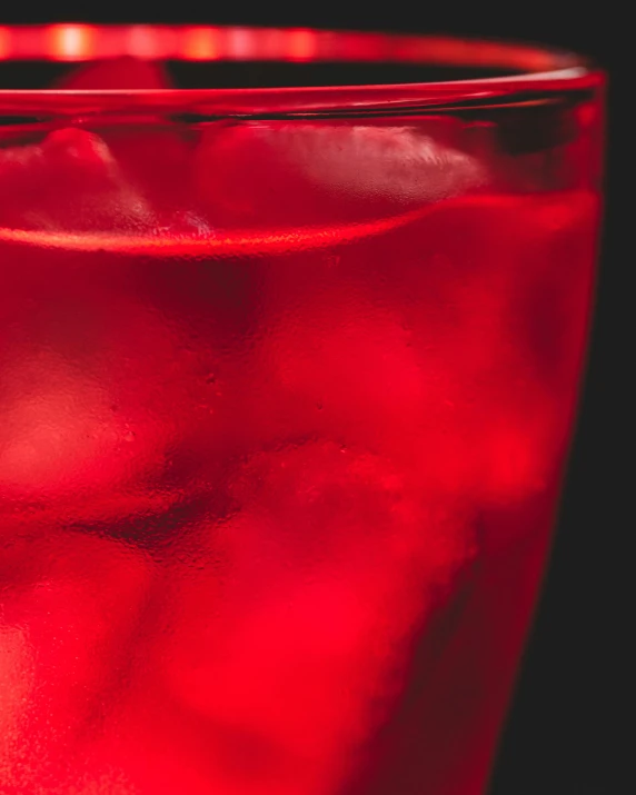 a red drink with ice cubes in a glass, an album cover, inspired by Dorothy Coke, pexels, renaissance, closeup - view, profile image, lemonade, monochromatic red