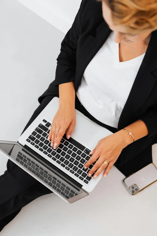 a woman sitting at a desk using a laptop computer, top - down photograph, highly polished, professionally assembled, full width