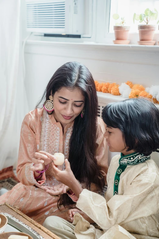 a woman and a child are sitting on the floor, inspired by Li Di, pexels contest winner, hurufiyya, wearing a silk kurta, holding a candle, easter, subtle detailing