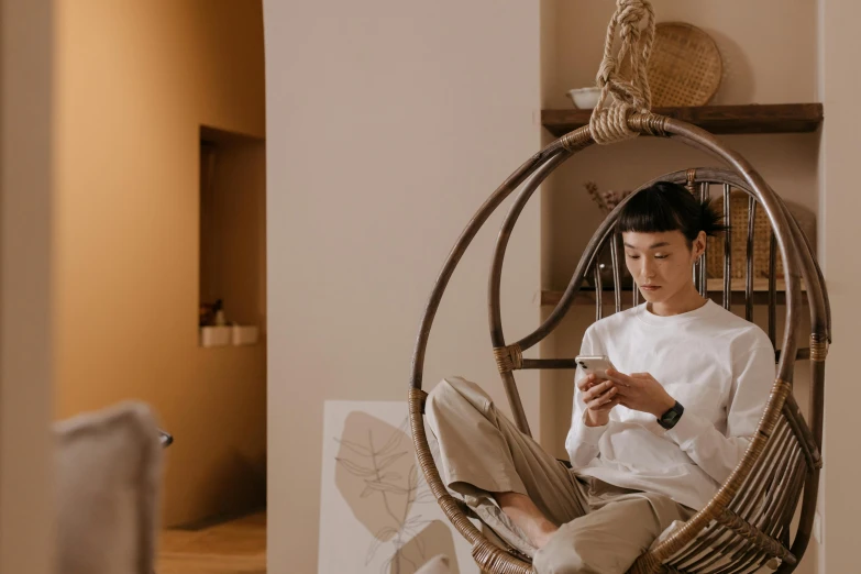 a man sitting in a hanging chair using a cell phone, by Jang Seung-eop, trending on pexels, visual art, an asian woman, trending onstudio ghibli, handsome chad chin, quy ho