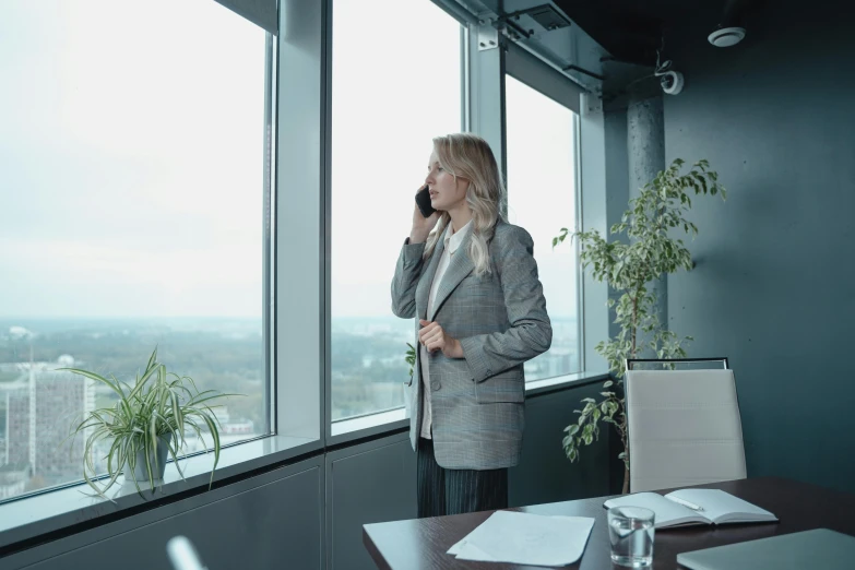 a woman talking on a cell phone in an office, a photo, by Emma Andijewska, pexels, realism, standing tall, looking out the window, фото девушка курит, a blond