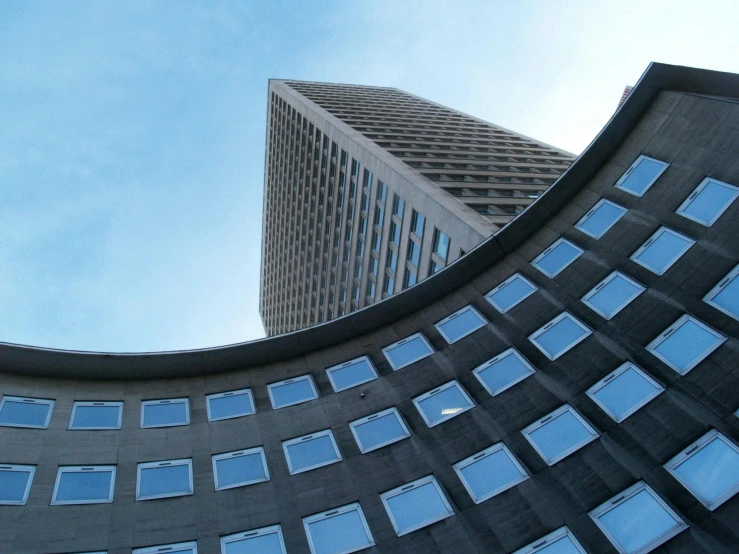 a couple of tall buildings next to each other, inspired by Ned M. Seidler, unsplash contest winner, brutalism, worm\'s eye view, mies van der rohe, geometric curves, 2 0 0 0's photo