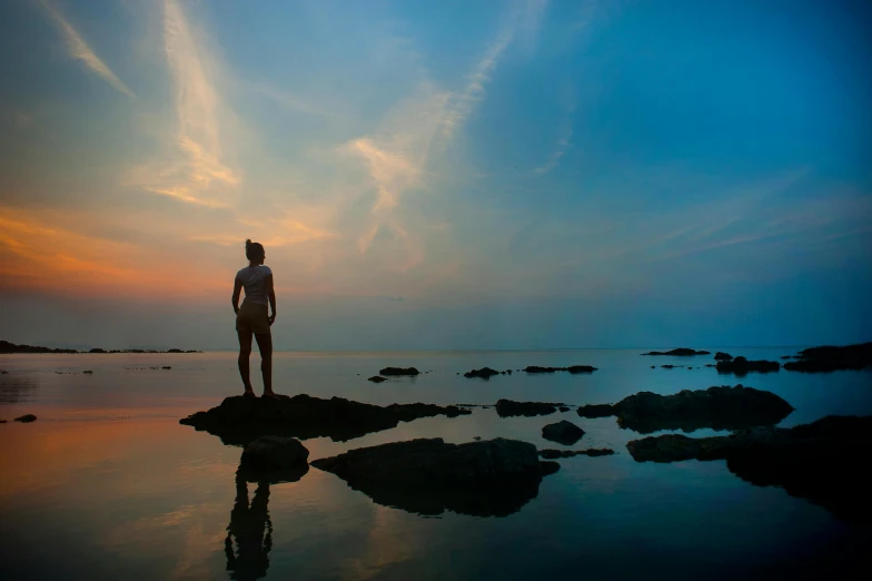 a man standing on top of a rock next to the ocean, pexels contest winner, minimalism, girl watching sunset, rock pools, full body image, floating into the sky