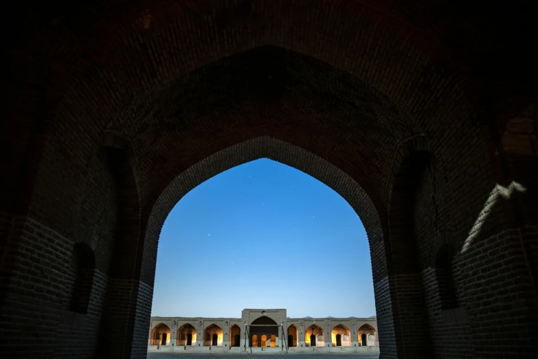 a view of a building through an archway, by Kamāl ud-Dīn Behzād, unsplash contest winner, arabesque, under the moon, equirectangular, dezeen, ground - level view
