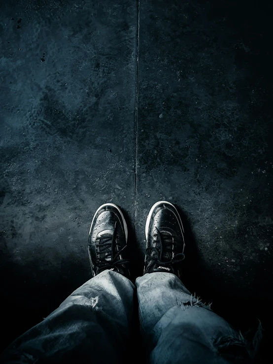 a person standing in a dark room with their feet on the floor, an album cover, pexels contest winner, fear of heights, leather shoes, profile image, dark blue and black