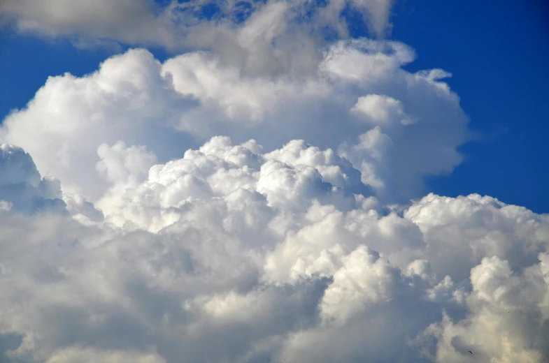 a plane flying through a cloudy blue sky, by Jan Rustem, unsplash, romanticism, giant cumulonimbus cloud, “puffy cloudscape, 2000s photo