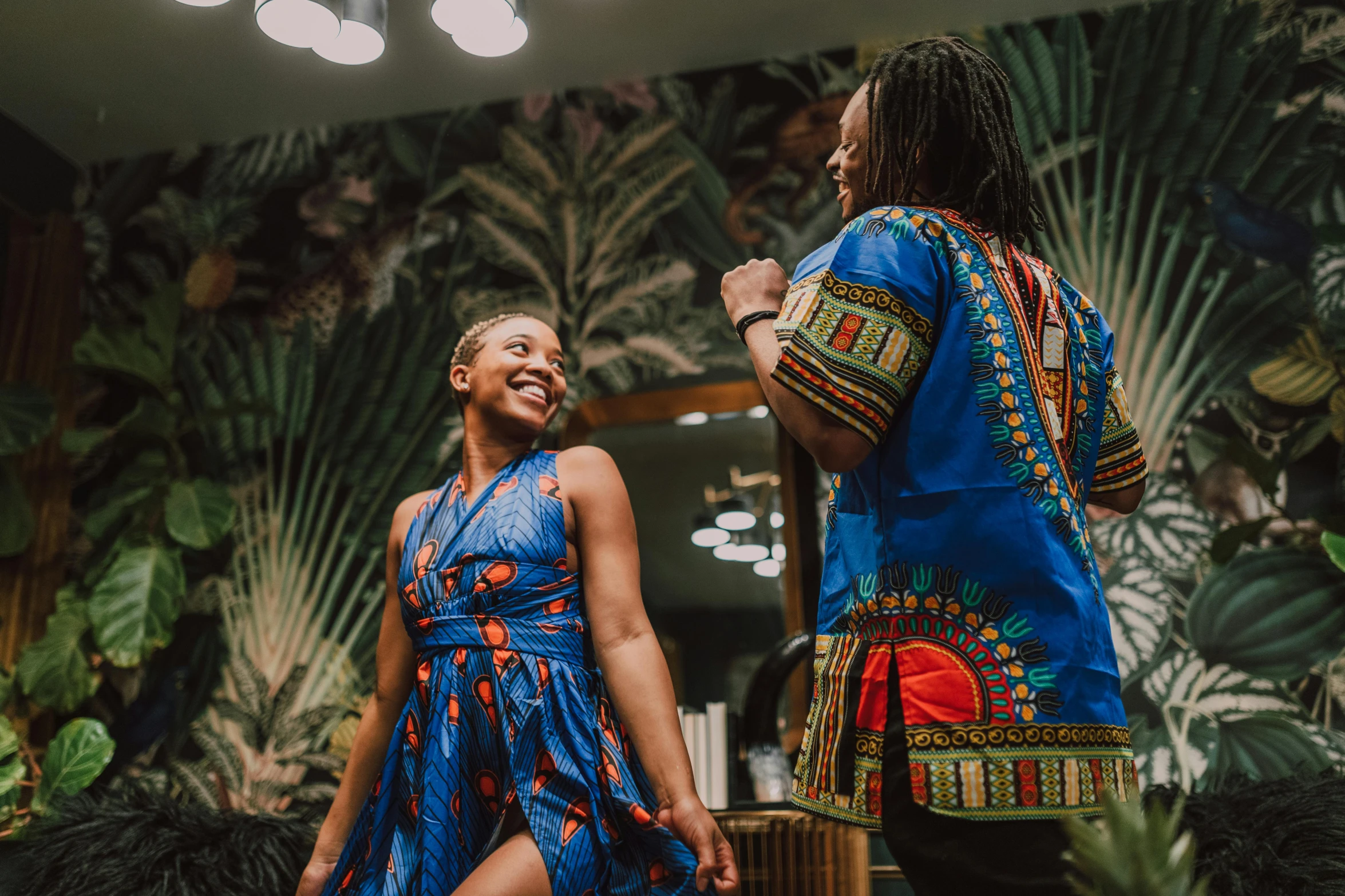 a man standing next to a woman in a blue dress, pexels contest winner, black arts movement, having fun. vibrant, wearing an african dress, promotional image, delightful surroundings