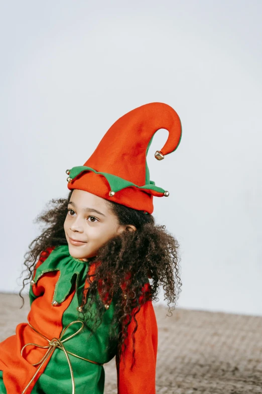 a little girl dressed in an elf costume, pexels contest winner, renaissance, pointy hat, orange jumpsuit, next gen, holiday vibe