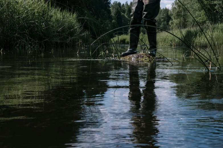 a man standing on top of a river holding a fish, by Jaakko Mattila, unsplash, hurufiyya, wet feet in water, water line surface, tarmo juhola, hd footage