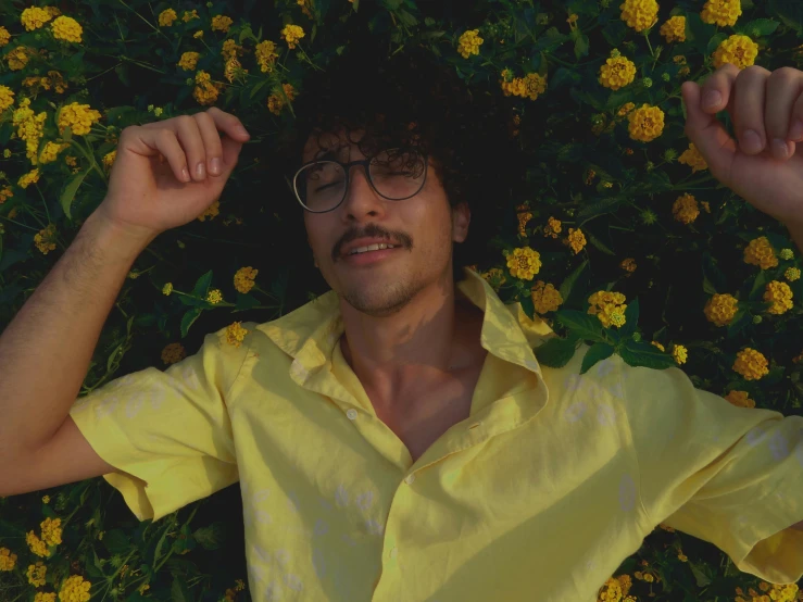 a man laying in a field of yellow flowers, an album cover, inspired by Leo Leuppi, pexels, unibrow, robert sheehan, man with glasses, movie still frame