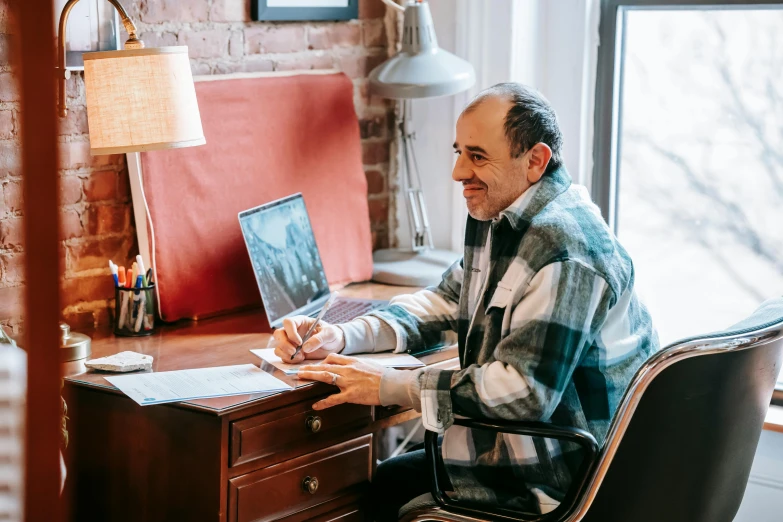 a man sitting at a desk working on a laptop, by Carey Morris, pexels contest winner, middle aged man, instagram post, signed, wholesome