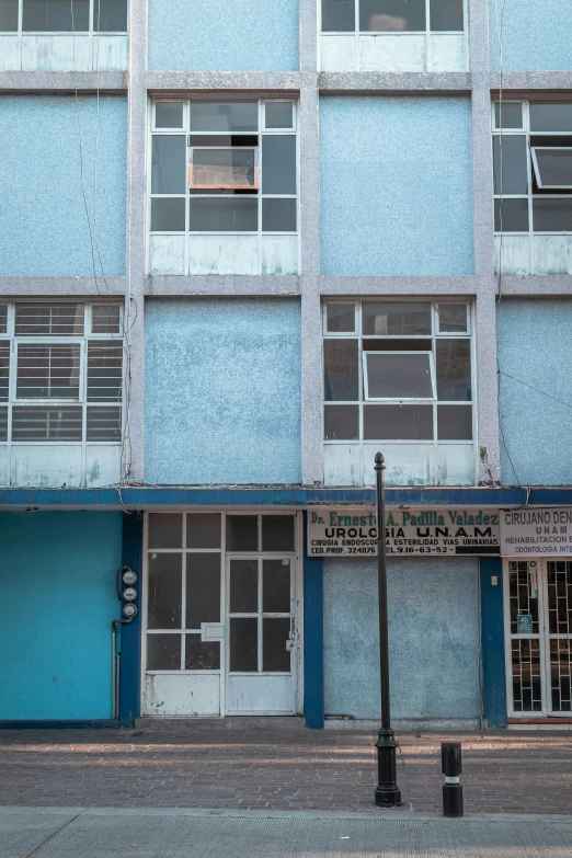 a tall blue building sitting on the side of a street, by Elsa Bleda, quito school, cuba, office/thrift store/social hall, white and pale blue, brutalist