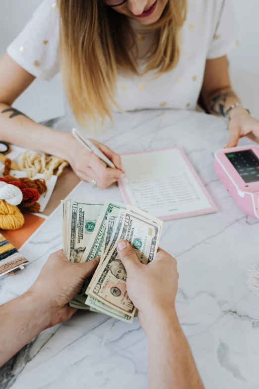 a man and woman sitting at a table with money, pexels contest winner, 🎀 🍓 🧚, jen atkin, getting groceries, with notes