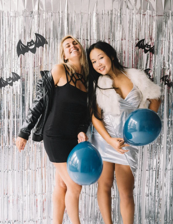 a couple of women standing next to each other, a polaroid photo, trending on unsplash, happening, party balloons, blue silver and black, halloween decorations, ruan jia and brom