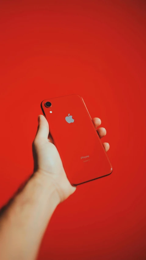 a person holding an iphone in their hand, pexels, symbolism, dominating red color, 2 5 6 x 2 5 6, enamel, low quality photo