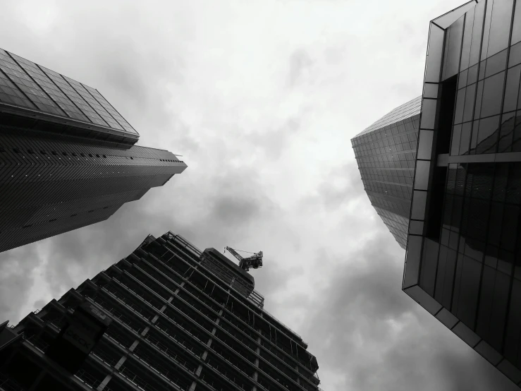 a black and white photo of skyscrapers in a city, pexels contest winner, three towers, crazy angle, gray sky, wide angel shot from below