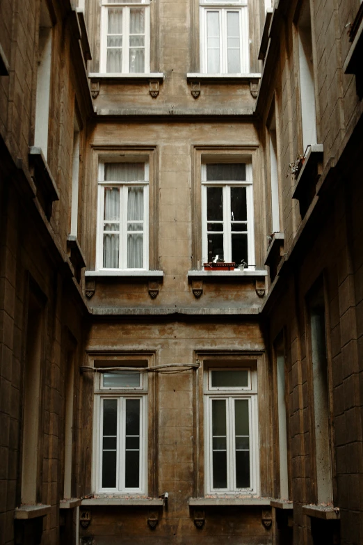 a person sitting in a window of a building, budapest, maze of streets, very aesthetically pleasing, little windows