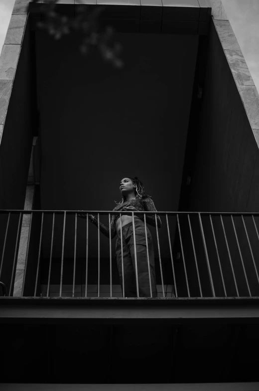 a man standing on a balcony talking on a cell phone, a black and white photo, pexels contest winner, conceptual art, female ascending, looking up at the camera, bella poarch, ((portrait))