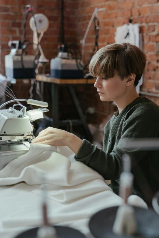 a man working on a sewing machine in a factory, by Toss Woollaston, trending on unsplash, arts and crafts movement, photo of young woman, wearing a labcoat, ignant, mary jane ansell