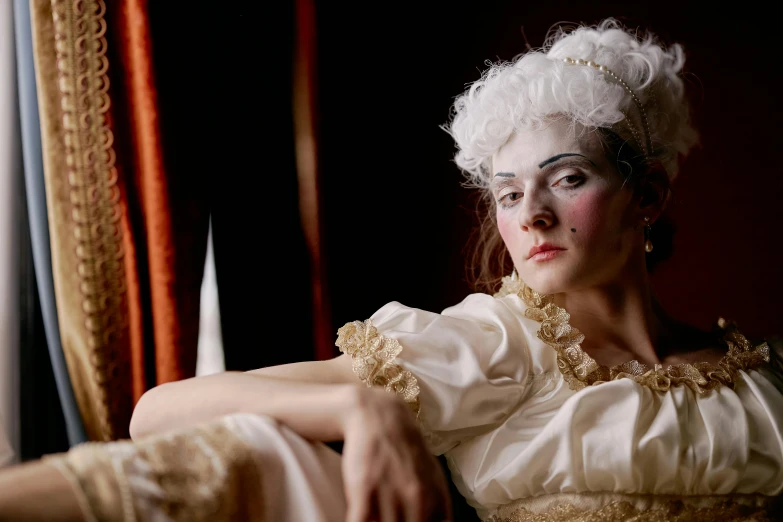 a woman in a white dress sitting in a chair, a portrait, inspired by Thomas Stothard, flickr, rococo, white face paint, film still from the movie, intense look, in a fancy dress