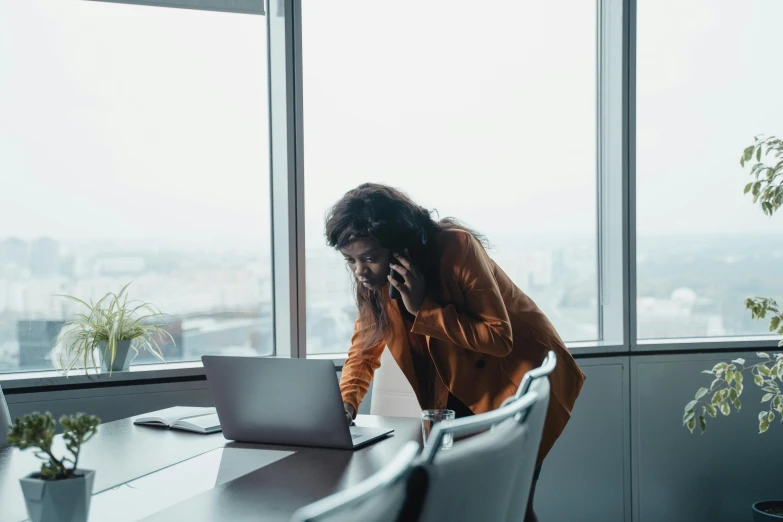 a woman sitting at a table talking on a cell phone, trending on pexels, in a foggy office, avatar image, bending down slightly, laptop