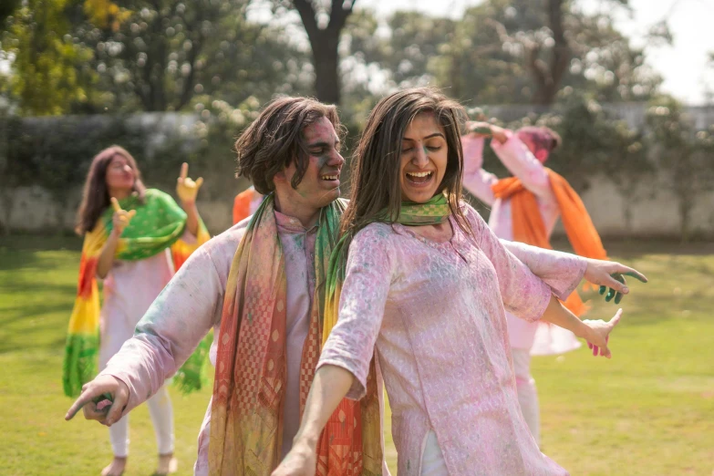 a couple of women standing on top of a lush green field, pexels contest winner, color field, dressed in a jodhpuri suit, wearing a tie-dye shirt, people dancing in background, wearing a fancy dress