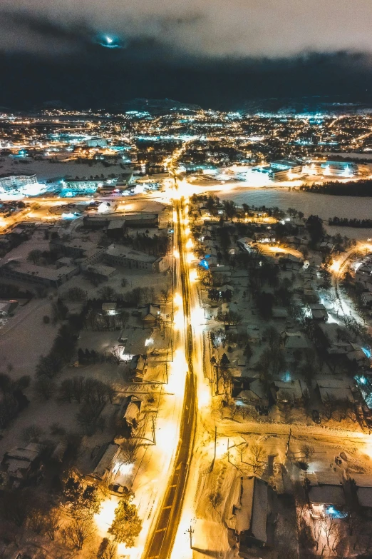 an aerial view of a city at night, by Matt Cavotta, unsplash contest winner, happening, snow glow, small town, yellow lights, carson ellis