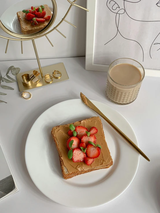 a white plate topped with a piece of cake next to a cup of coffee, 🎀 🧟 🍓 🧚, material brass & copper gold, next to sliced strawberries, humus