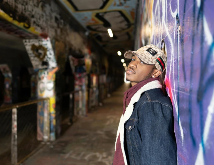 a man leaning against a wall with graffiti on it, inspired by Gerard Sekoto, pexels contest winner, stood in a tunnel, black teenage boy, natural lights, multicoloured