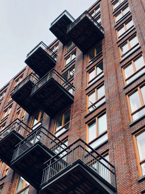 a tall brick building with many balconies on it, by Kristian Zahrtmann, pexels contest winner, modernism, industrial buildings, architectural finishes, eyelevel perspective image, multiple stories