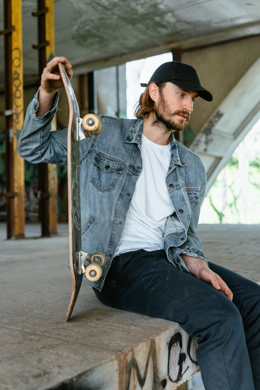 a man sitting on a ledge holding a skateboard, a portrait, trending on pexels, photorealism, wearing double denim, promotional image, profile image, wears a destroyed hat