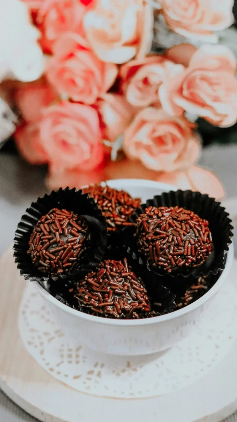 a bowl of chocolates sitting on top of a white plate, inspired by Rudolf von Alt, pexels, hurufiyya, balls of rice, bouquet, dark brown, blushing