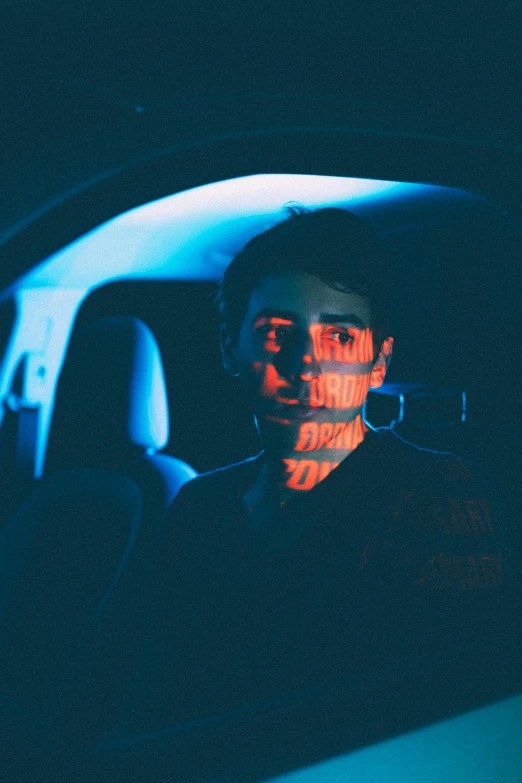 a man sitting in the passenger seat of a car, inspired by Elsa Bleda, holography, declan mckenna, red neon eyes, portrait featured on unsplash, press shot
