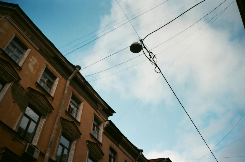 a street light hanging off the side of a building, by Tamas Galambos, unsplash, floating power cables, russian architecture, taken in the mid 2000s, view from ground