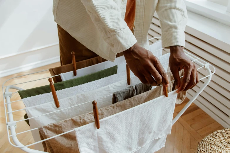 a close up of a person holding a laundry basket, by Matija Jama, pexels contest winner, silk tarps hanging, lined up horizontally, brown and white color scheme, designer product