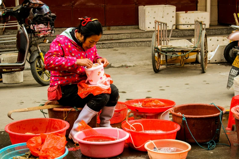 a woman sitting on top of a pile of buckets, a silk screen, by Julia Pishtar, pexels contest winner, sichuan, square, fishing, ready to eat