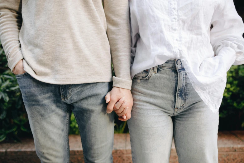 a man and a woman standing next to each other, trending on pexels, thigh gap, holding each other hands, white and grey, conservatively dressed