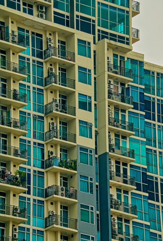 a tall building with lots of windows and balconies, by Dan Scott, contrasted colors, modern neighborhood, green and blue, low iso