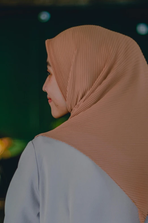 a close up of a person wearing a hijab, inspired by Nazmi Ziya Güran, trending on pexels, calm night. over shoulder shot, light tan, panels, indonesia