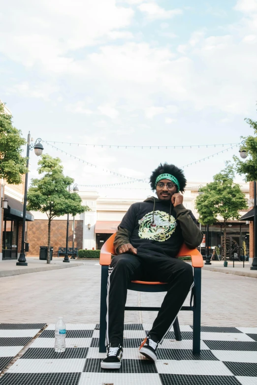 a man sitting on a chair talking on a cell phone, inspired by Washington Allston, trending on unsplash, black arts movement, avacado chairs, curls on top of his head, southdale center, trees around