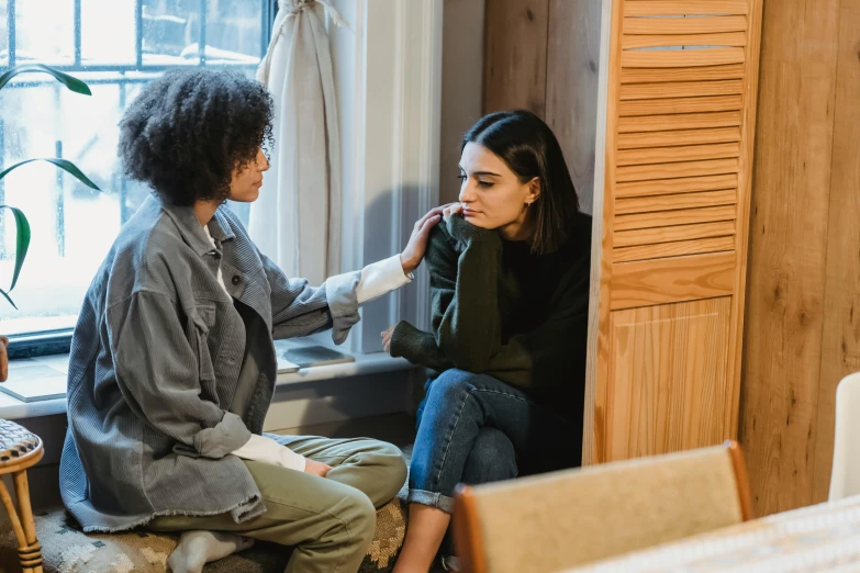 a woman combing another woman's hair in front of a window, trending on pexels, antipodeans, sitting on a couch, people crying, lesbian, in small room