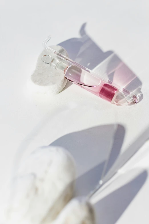 a toothbrush sitting on top of a white table, inspired by Anna Füssli, floating in perfume, shades of pink, hibernation capsule close-up, translucent sss