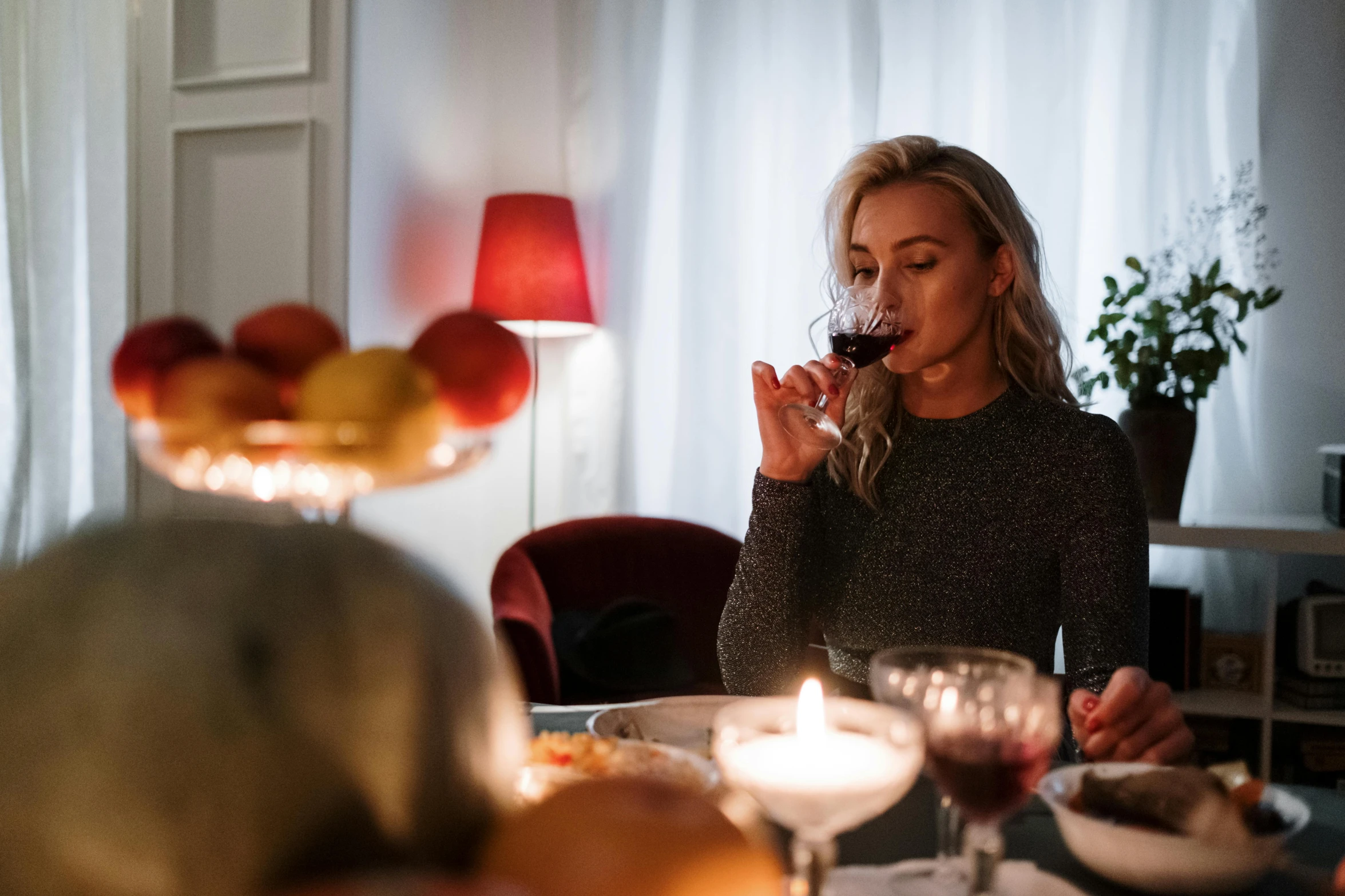 a woman sitting at a table with a glass of wine, by Jesper Knudsen, pexels contest winner, family dinner, christmas night, profile image, autumn season