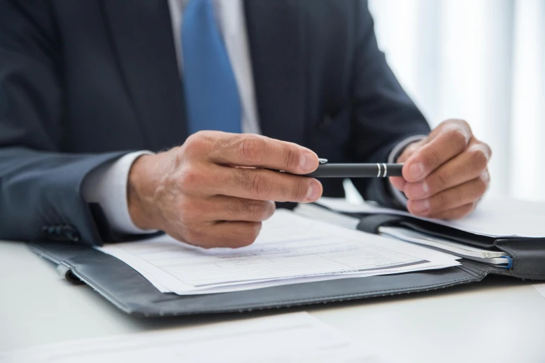 a man in a suit sitting at a desk with a pen in his hand, pexels, private press, holding a clipboard, selling insurance, official screenshot, multiple stories