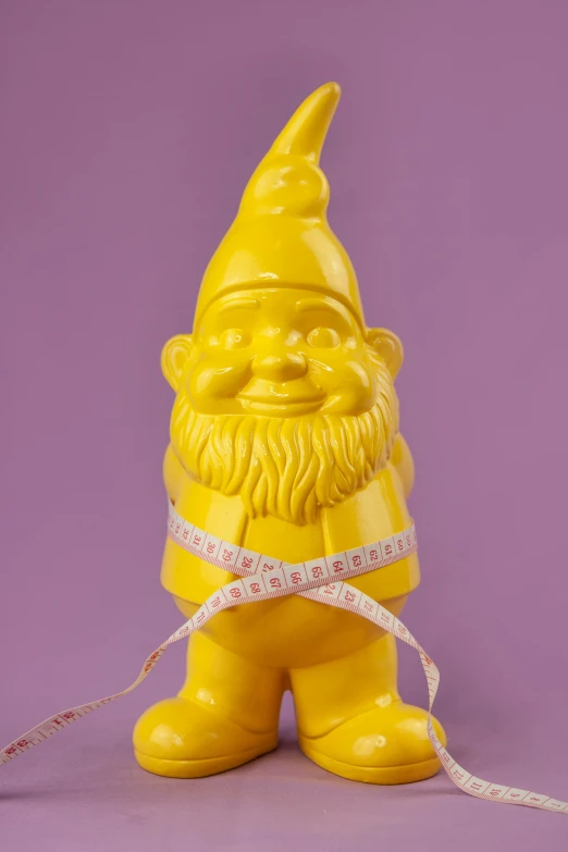 a yellow statue of a gnome holding a measuring tape, inspired by Sarah Lucas, reddit, off - white collection, retired barney, professional product photo, made of rubber