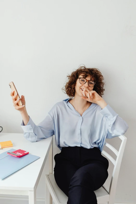 a woman sitting at a table with a cell phone in her hand, trending on pexels, happening, funny and silly, office clothes, curly haired, instagram picture